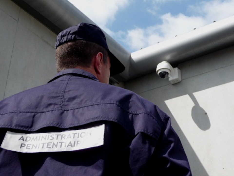 Deux individus essayent de lancer des paquets à un détenu