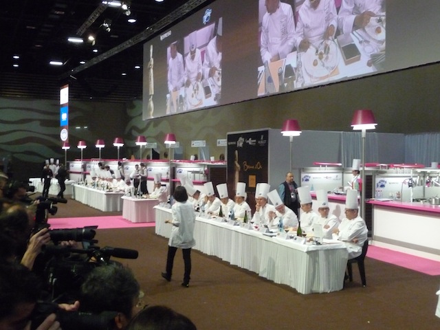 Un candidat en pleine préparation, entouré par son coach et les cols tricolores du jury.